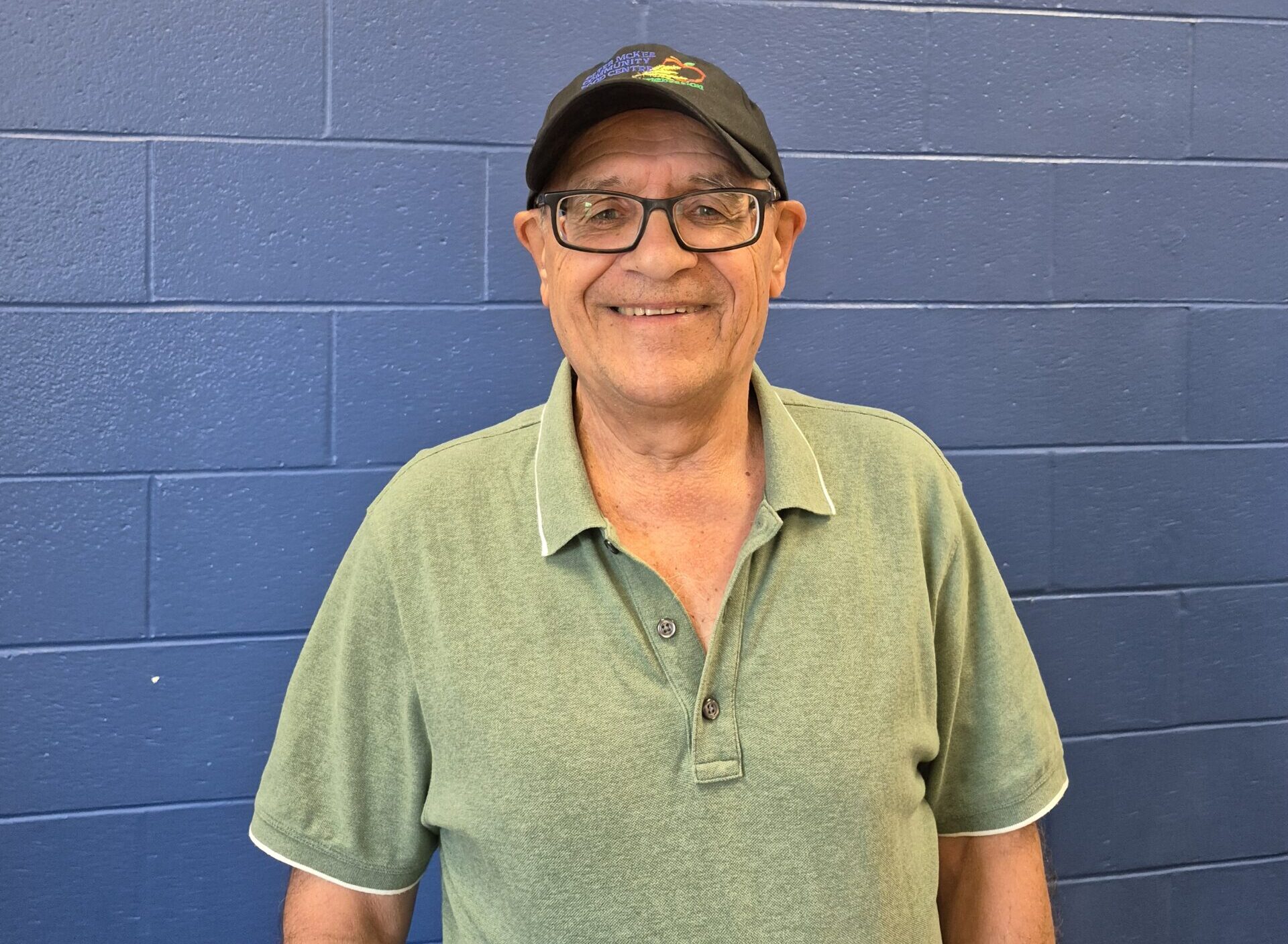 Portrait of a Peter McKee Community Centre team member wearing a green polo and a cap