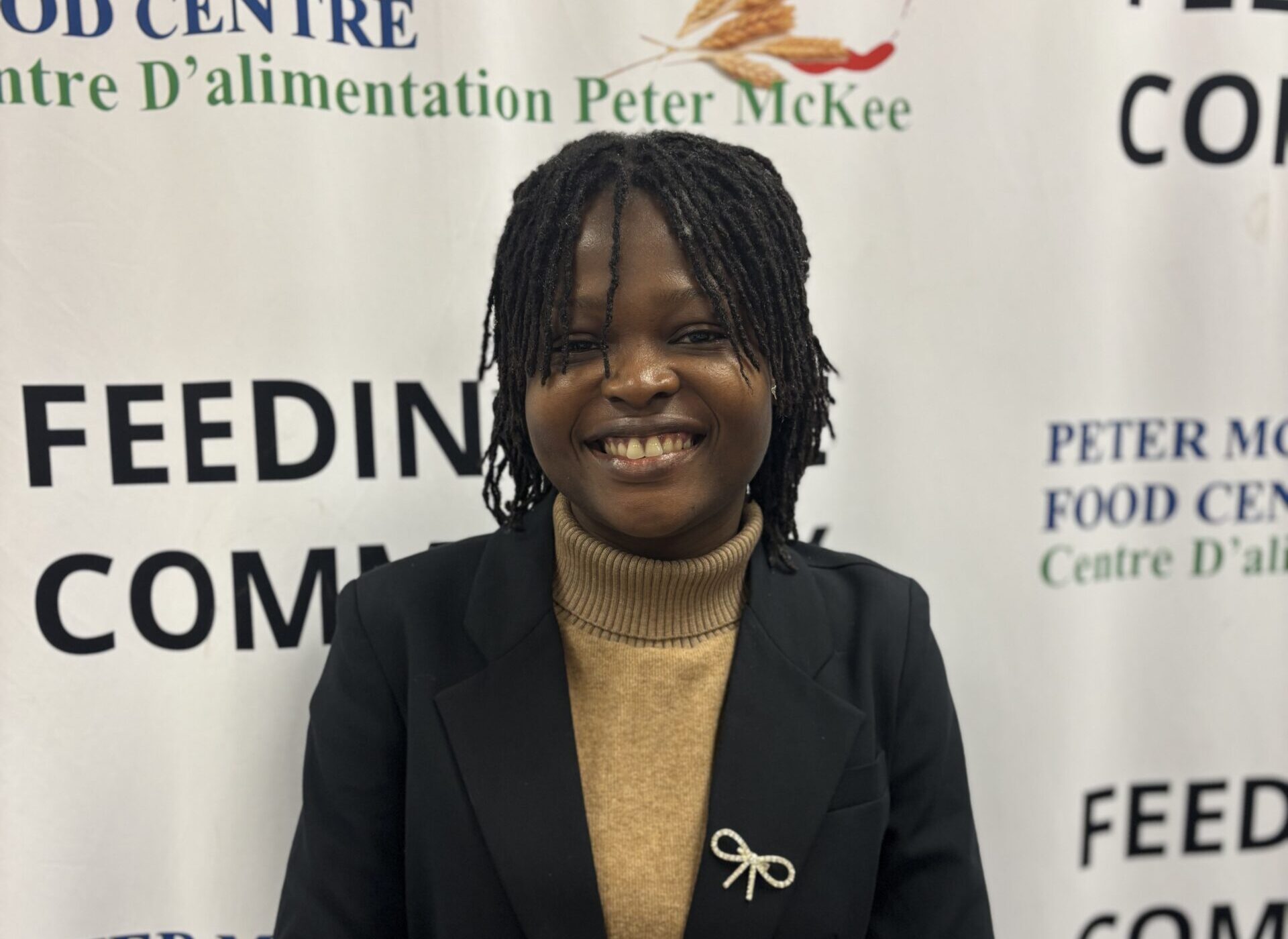 Smiling Peter McKee Community Centre team member standing in front of branded banners
